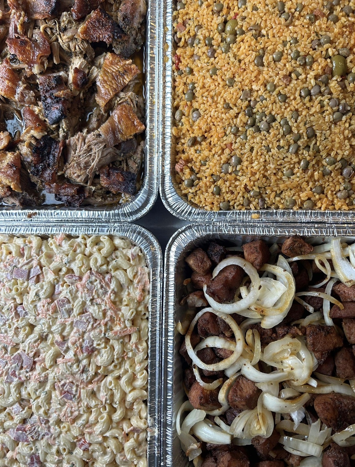 Puerto Rican catering trays with pernil, rice, pasta salad and sausage